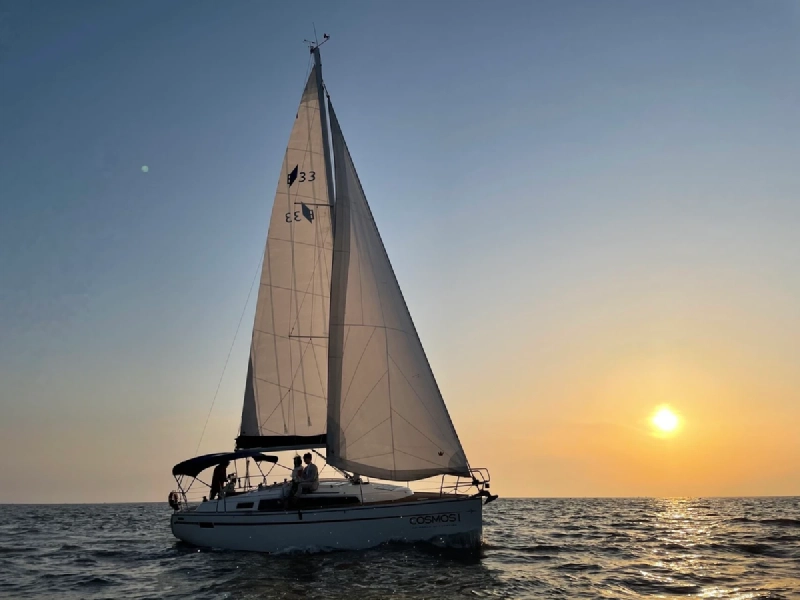 夕暮れの仁川の海を帆走するヨットと、水平線に沈む夕日